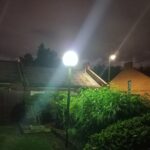 A bright&nbsp;lamp-post&nbsp;and streetlight under a cloudy, light-polluted sky