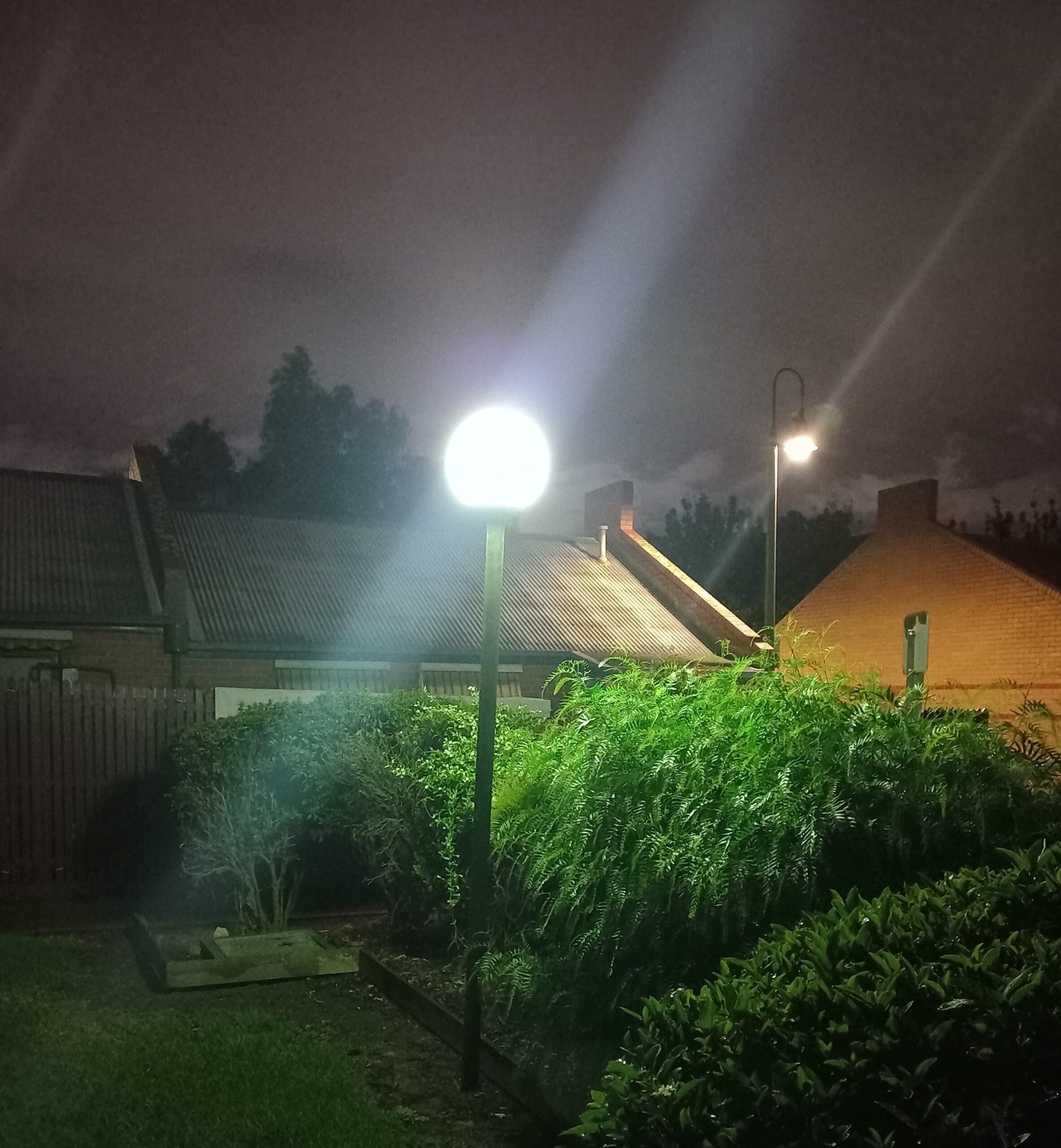 A bright lamp-post and streetlight under a cloudy, light-polluted sky